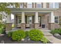 Inviting front porch with stone columns and seating, complemented by manicured landscaping and stone pathway at 13485 Mancroft Dr, Fishers, IN 46037