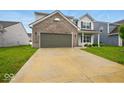 View of home with a brick facade, gray siding, well-maintained lawn, and concrete driveway at 1454 Silver Pine Ln, Sheridan, IN 46069