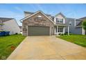 View of the home's two car garage and driveway with a manicured front lawn during daylight at 1454 Silver Pine Ln, Sheridan, IN 46069