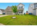 Home's manicured front yard and light gray exterior, complemented by a young, vibrant tree at 1454 Silver Pine Ln, Sheridan, IN 46069