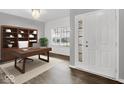 Bright office features a built-in bookshelf, a dark wood desk, with a large window and white entry door at 1454 Silver Pine Ln, Sheridan, IN 46069