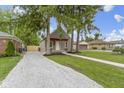View of the charming home's front exterior, featuring a red porch, gravel driveway, and green lawn at 2046 N Tibbs Ave, Indianapolis, IN 46222