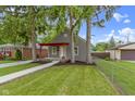 A quaint home displays a red porch and green lawn, framed by mature trees at 2046 N Tibbs Ave, Indianapolis, IN 46222