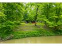 Scenic view of a cozy home with bright red outdoor chairs, surrounded by lush greenery and river at 2781 E Vandalia Rd, Flat Rock, IN 47234