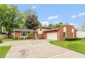 Traditional home exterior boasts a two-car garage, brick accents, and a spacious driveway, surrounded by lush trees at 3514 Summerfield Dr, Indianapolis, IN 46214