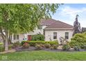 Beautiful brick home featuring lush landscaping, colorful flowers, and mature trees creating a welcoming entrance at 3655 Copperleaf Blvd, Greenwood, IN 46143