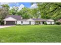 Well-maintained home with large front yard, mature trees, and a spacious two-car garage at 445 W 63Rd St, Indianapolis, IN 46260