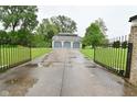 Gated driveway leads to a spacious three-car garage, surrounded by lush greenery and trees at 5135 Moller Rd, Indianapolis, IN 46254