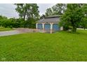 View of a large three-car garage with blue doors, surrounded by green lawns and mature trees at 5135 Moller Rd, Indianapolis, IN 46254