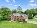 Aerial view of a well-maintained brick home, showcasing the roof, lawn, and surrounding trees at 5313 Redbird Dr, Columbus, IN 47201