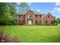 A spacious front yard highlights this two-story brick house, complemented by lush greenery and mature trees at 5313 Redbird Dr, Columbus, IN 47201