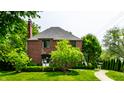 Brick home featuring manicured lawn, lush landscaping, and a winding stone walkway at 5401 N New Jersey St, Indianapolis, IN 46220