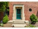 Close-up of brick home's entrance, showcasing a teal door and manicured greenery at 5401 N New Jersey St, Indianapolis, IN 46220