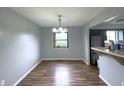 A dining room featuring wood-look flooring, a modern chandelier, and a view into the kitchen area at 5760 Tim Tam Ct, Indianapolis, IN 46237
