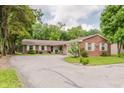View of charming single story brick home featuring an asphalt driveway and mature landscaping at 6030 Riverview Dr, Indianapolis, IN 46208