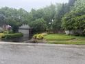 View of home's front yard, featuring mature trees and a driveway leading to a garage at 6609 N Tuxedo Ln, Indianapolis, IN 46220