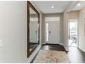 Bright hallway featuring hardwood floors, a large mirror, and a view of the front door at 9352 Corbett Dr, McCordsville, IN 46055