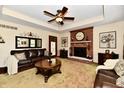 Spacious living room with a brick fireplace, ceiling fan, and comfortable leather furniture at 1010 Lakewood N Dr, Brownsburg, IN 46112