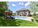 Relaxing backyard pool area featuring lounge chairs, umbrellas, and lush landscaping for outdoor enjoyment at 13909 Waterway Blvd, Fishers, IN 46040