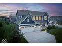 Beautiful home with a two-car garage and manicured lawn at dusk in a suburban neighborhood at 16598 Dominion Dr, Fortville, IN 46040