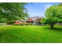 Traditional ranch home with green lawn, mature trees, and brick exterior at 2027 Round Barn Ct, Anderson, IN 46017