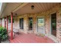 Charming covered front porch with a wooden bench and red brick exterior at 2027 Round Barn Ct, Anderson, IN 46017