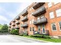 Red brick apartment building with charming balconies and well-maintained grassy landscaping at 55 S Harding St # 308, Indianapolis, IN 46222