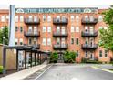 The H. Lauter Lofts, a red brick apartment building, featuring charming balconies and beautiful greenery at 55 S Harding St # 308, Indianapolis, IN 46222