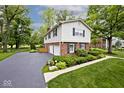 Charming two-story home featuring a mix of brick and siding, complemented by mature trees and manicured landscaping at 6115 E 65Th Pl, Indianapolis, IN 46220