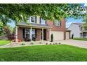 Inviting front yard with lush green lawn, landscaping, a cozy porch, and a brick and siding exterior at 7312 Drum Castle Ct, Indianapolis, IN 46259