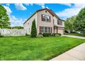 Inviting home with a well-maintained lawn, white picket fence, and a combination of brick and vinyl siding at 9001 Harrison Run Ct, Indianapolis, IN 46256