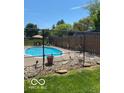 Backyard pool area surrounded by chain link fence and decorative rock, with shaded seating and patio at 1425 Winding Trail Cir, Greenwood, IN 46142
