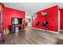 Open-concept living room with laminate floors, red accent wall, TV, and bar stools at 2730 Foxbriar Pl, Indianapolis, IN 46203