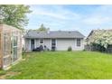 Spacious backyard featuring a greenhouse, grassy area, and mature trees at 305 W Vinyard St, Anderson, IN 46011