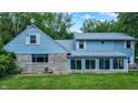 Charming home exterior featuring light blue siding, stone accents and lots of bright windows at 6430 E Southport Rd, Indianapolis, IN 46237
