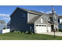 Side view of a beautiful gray home with an attached two-car garage and lush green lawn at 8876 Boylan Pl, Pendleton, IN 46064