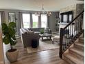 Beautifully decorated living room with gray walls, stone fireplace, and modern chandelier lighting at 8876 Boylan Pl, Pendleton, IN 46064