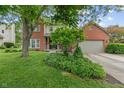 Two-story home with brick accents, lush landscaping, a mature tree, and attached two car garage at 10501 Greenway Dr, Fishers, IN 46037