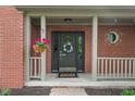 Inviting front entrance with a black door, decorative wreath, sidelights, and hanging flower basket at 10501 Greenway Dr, Fishers, IN 46037