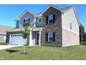 Attractive two-story home boasts a combination of brick and siding with a manicured lawn and young tree at 1056 Bent Branch Ln, Greenwood, IN 46143