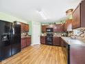A functional kitchen featuring wood cabinets, black appliances, tile backsplash, and laminate flooring at 1117 Oregon Way, Anderson, IN 46012