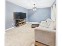 Cozy living room features plush carpeting, a comfortable sofa, and a large screen television for ultimate relaxation at 1117 Oregon Way, Anderson, IN 46012