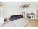Bright living room with a dark plush sofa, ceiling fan, decorative fireplace and a large area rug at 1117 Oregon Way, Anderson, IN 46012