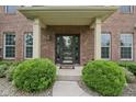 Charming brick home entrance with decorative shrubs, stone detail and glass paneled front door at 11844 Pine Meadow Cir, Fishers, IN 46037