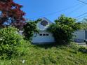 Detached two-car garage with a basketball hoop and overgrown foliage at 1433 N Denny St, Indianapolis, IN 46201