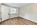 Bright bedroom with wood-look flooring, a window with blinds, neutral paint, and a white entry door at 1730 N Graham Ave, Indianapolis, IN 46218
