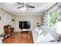 Cozy living room with wood floors, a gray sofa, a ceiling fan and large window providing natural light at 318 S Routiers Ave, Indianapolis, IN 46219