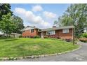 Well-maintained red brick home with a lush green lawn and colorful flowerbeds leading to the front door at 4614 Thornleigh Dr, Indianapolis, IN 46226