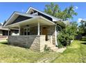 A quaint house with a yellow door, stone accents, and lush green lawn at 4814 E New York St, Indianapolis, IN 46201