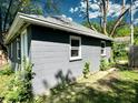 Exterior view of detached garage featuring a gray cinderblock exterior and three windows at 4814 E New York St, Indianapolis, IN 46201